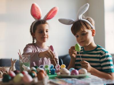 2 børn med kaninører maler påskeæg